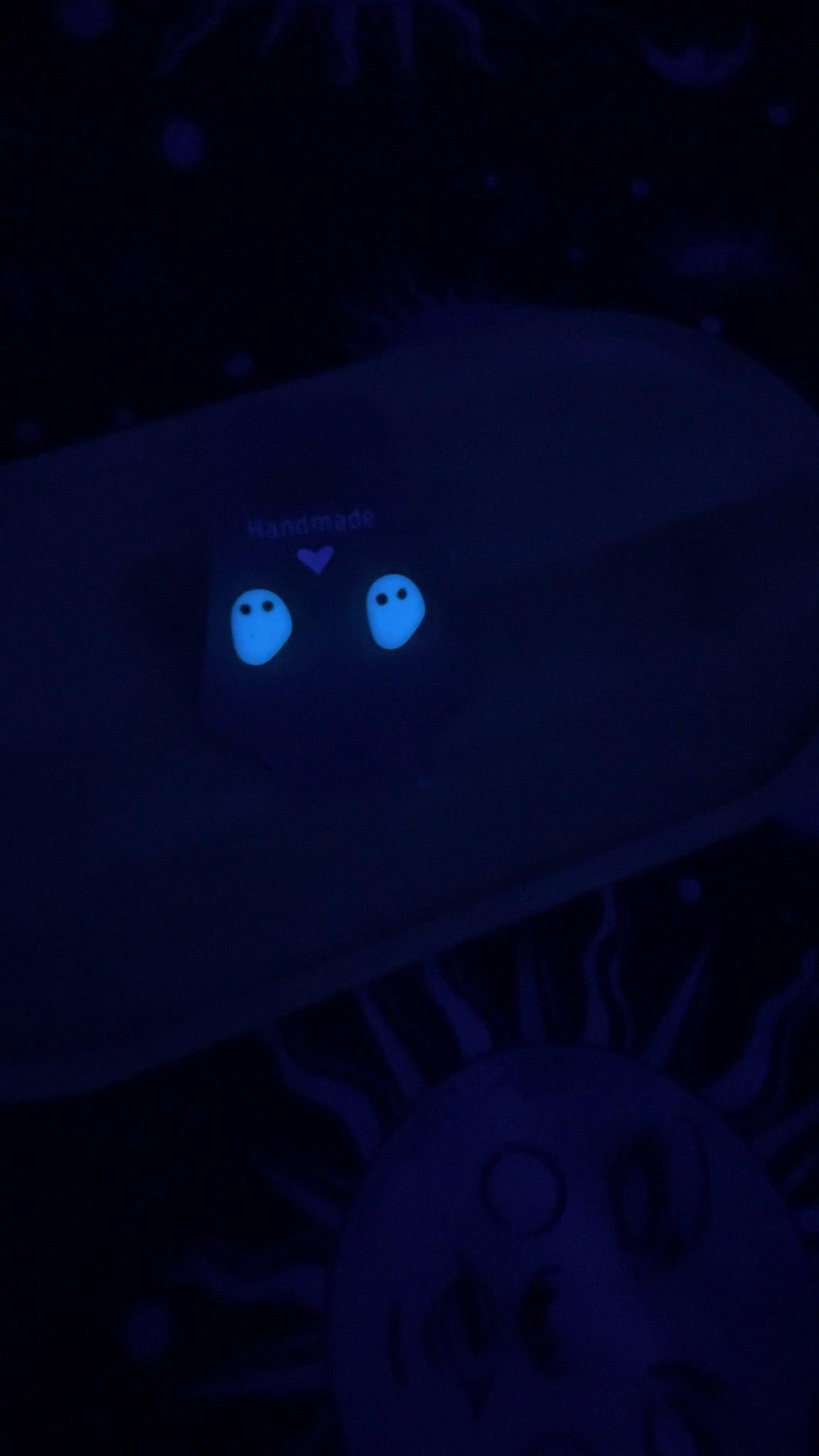 Handmade ghost earrings glowing in UV light 