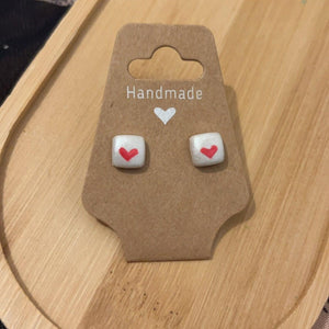 First love has white background with red love heart stud earrings. 